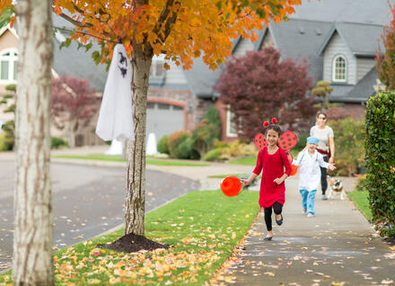 Children in Halloween costumes running on sidewalk