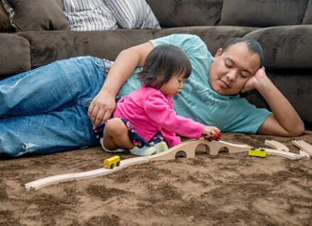 man watchng toddler play with toy train tracks