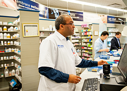 Pharmacist filling prescription at computer. Pharmacist filling prescription at computer.