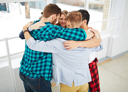 Group of young adults in circle with arms around each other. Group of young adults in circle with arms around each other.