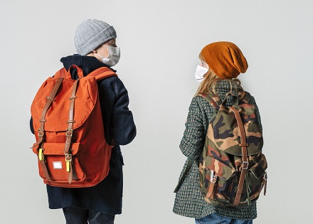 two kids in masks, coats and backpacks