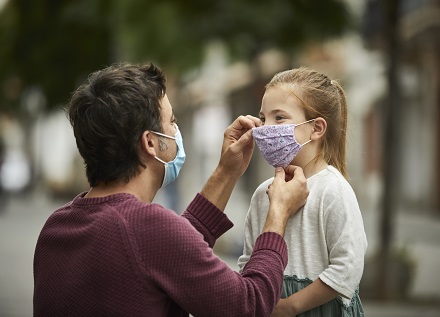 man helping child with face mask