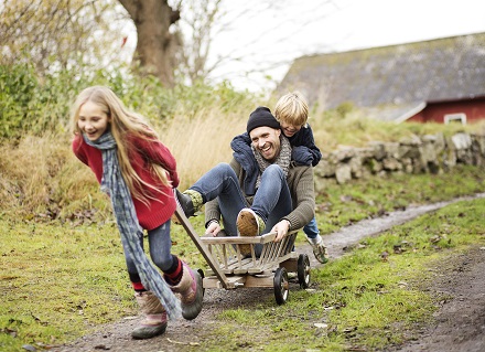 two kids and dad luaghing, playing outside
