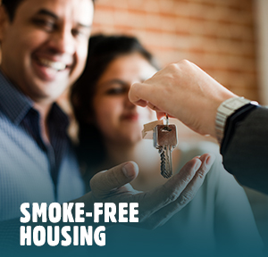 A smiling young couple gets handed the keys to their new home
