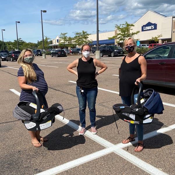 three staff people in parking lot with car seats