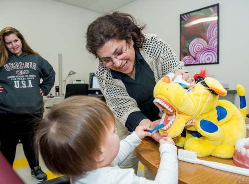 dental hygienist helping toddler look at stuffed animal's teeth 