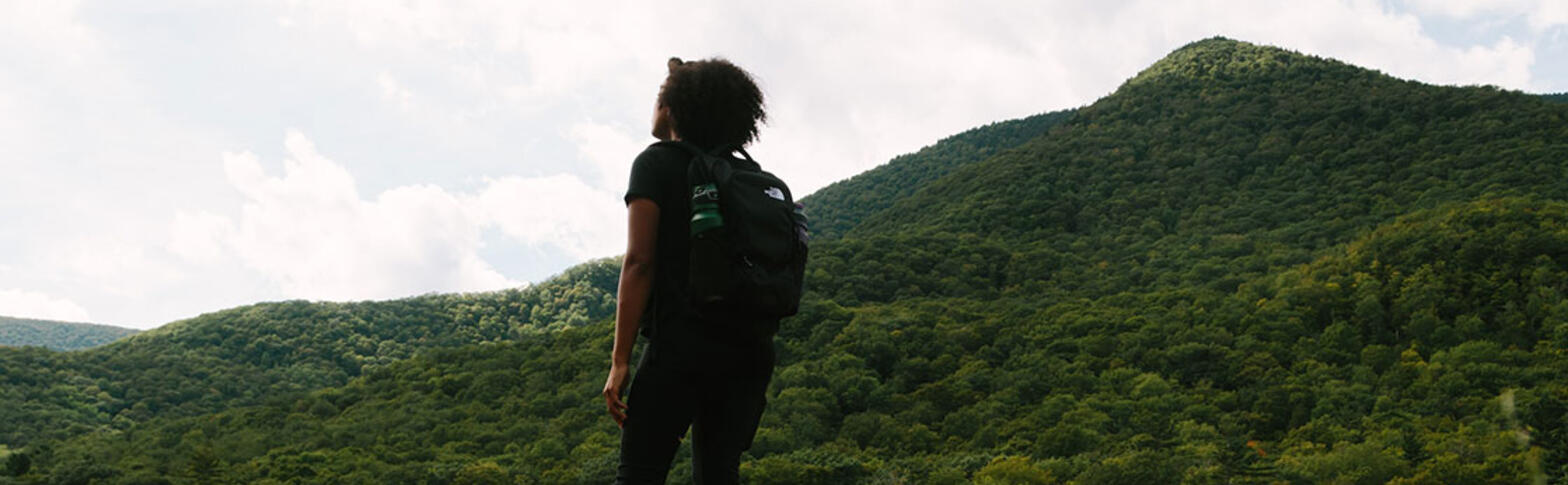 Woman standing in a green field of grass with a mountain in the back