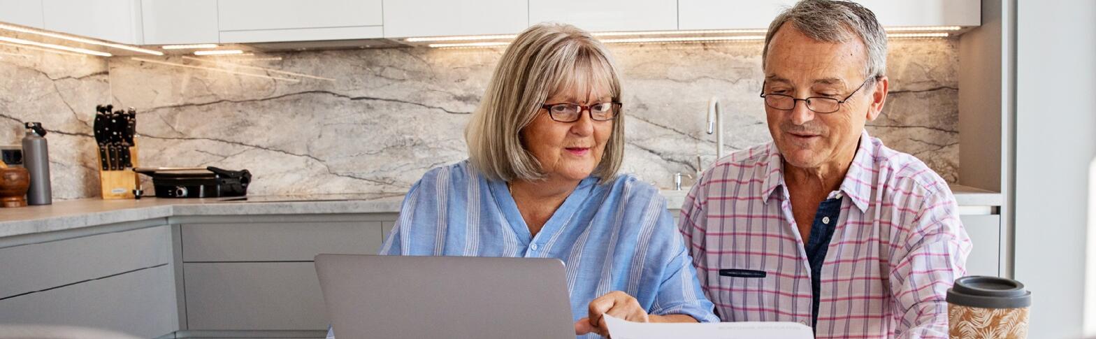two people in kitchen looking at paper and computer