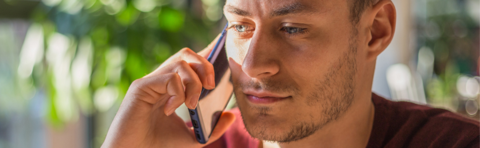 man in a red long sleeve shirt listening on a cell phone