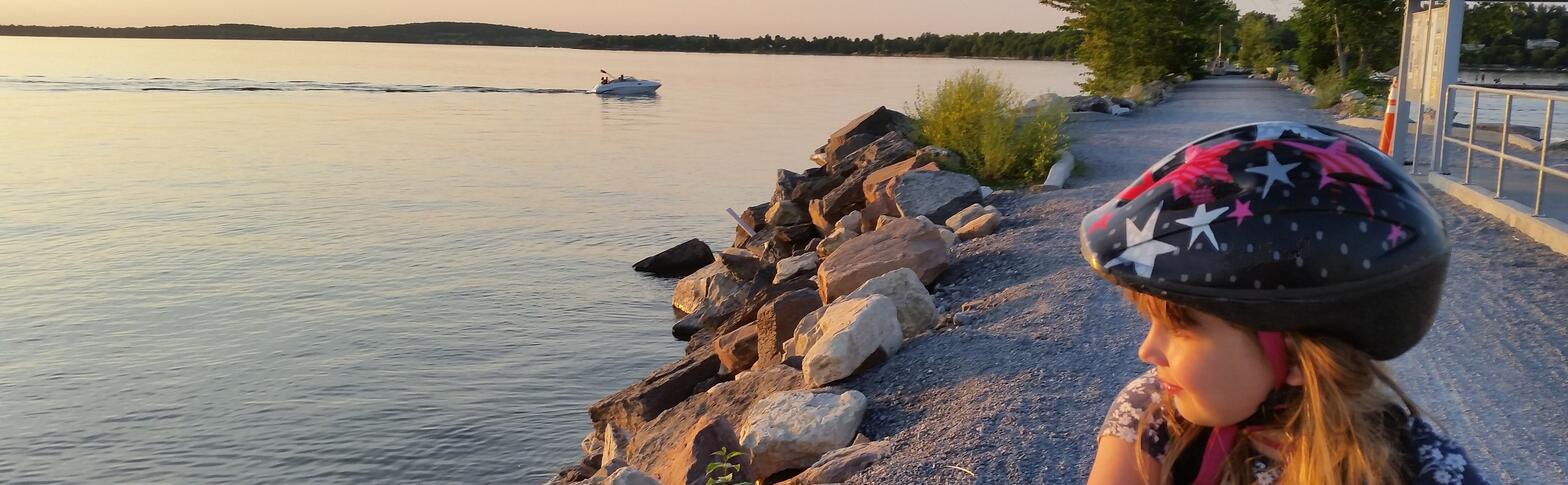 kid with bicycle helmet looking at Lake Champlain from the bike path