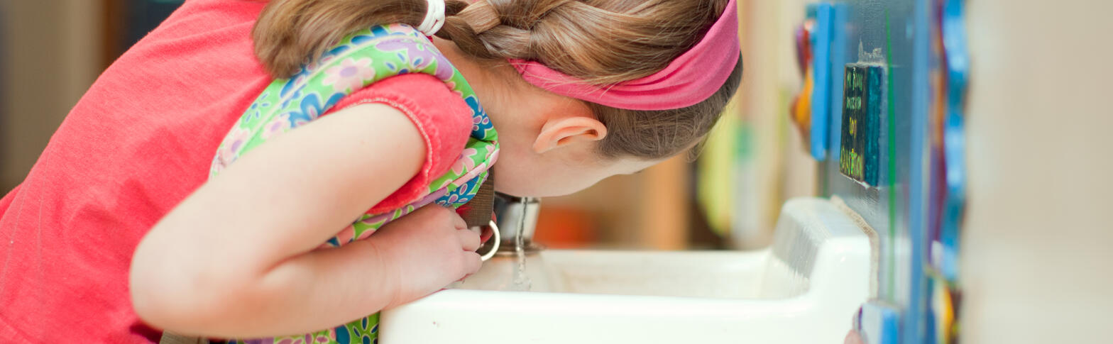 kid drinking from a water fountain at school