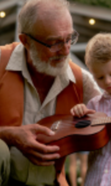 man playing guitar with his granddaughter