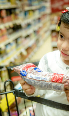 toddler with bag of beans in store