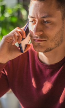 man in a red long sleeve shirt listening on a cell phone