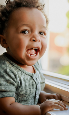 A toddler holding onto a windowsill.