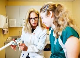 health professional looking at model knee with teen