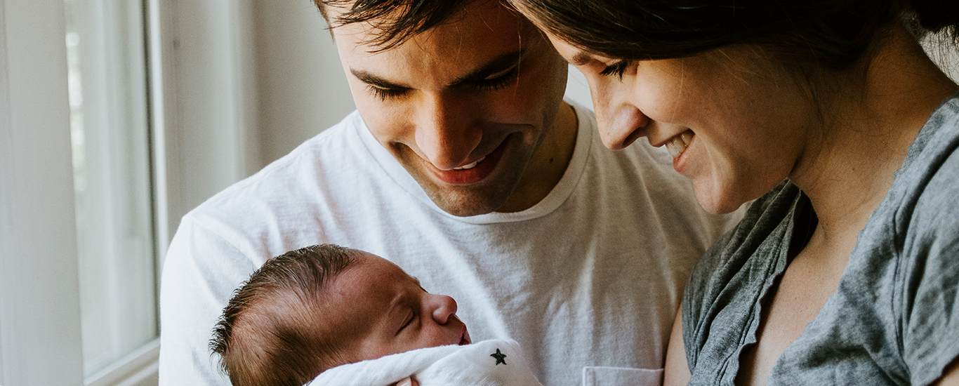 parents smiling at newborn baby