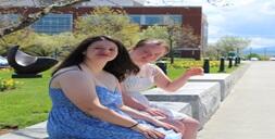 two-young-adults-sitting-in-front-of-a-building.