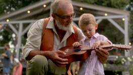 man playing guitar with his granddaughter