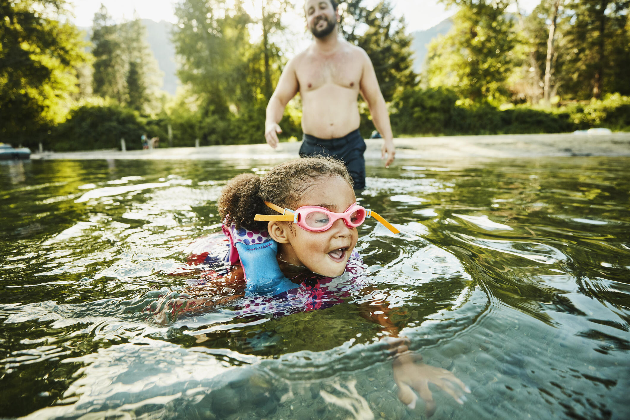girl swimming in a lake with goggles and floaties