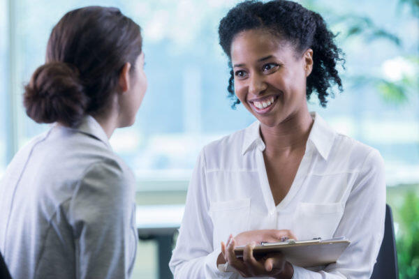 woman with clipboard talking to health care professional