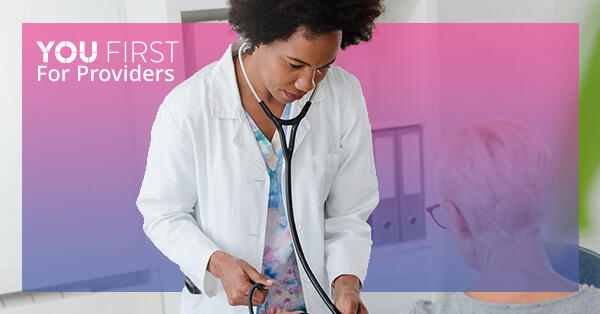 Health care provider using stethoscope with patient, with You First logo