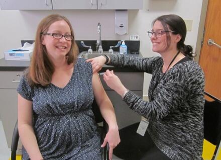 pregnant woman receiving immunization from nurse