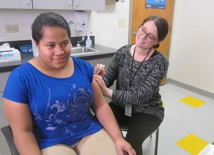 teen getting immunization from woman