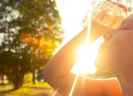 woman holding a water bottle to her head on a hot, sunny day