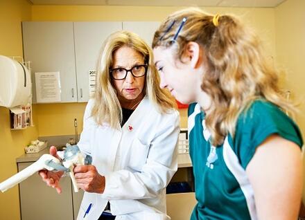 health professional looking at model knee with teen