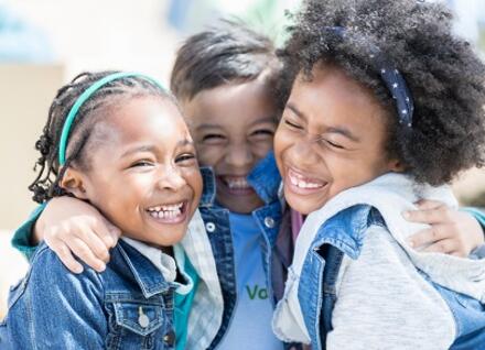 Little boy hugs his two sisters while volunteering at a community charity event