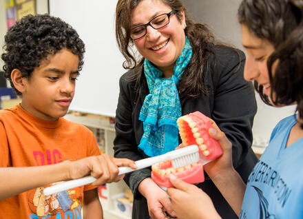 woman showing students model teeth