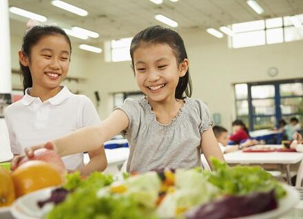 girl reaching for healthy food in school cafeteria