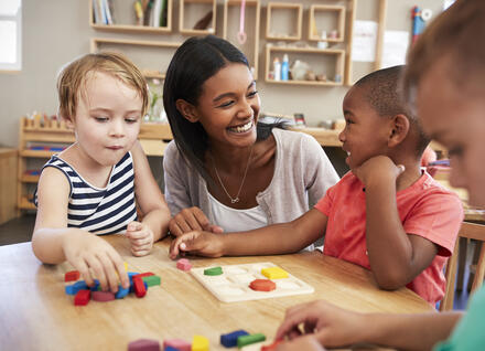 kids at a table drawing with a woman caregiver kids at a table drawing with a woman caregiver