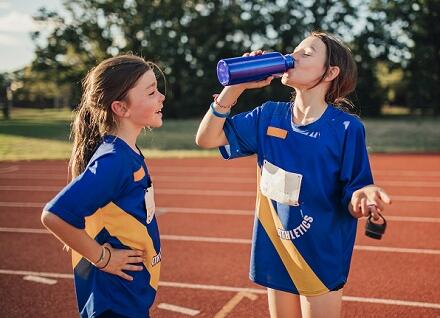 girls on track drinking water from bottle