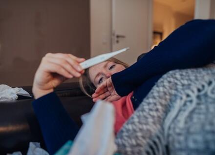 woman in bed with thermometer