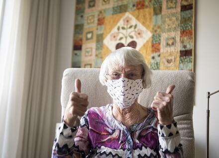 older woman wearing masks gives thumbs up