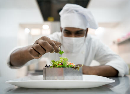 masked chef preparing salad