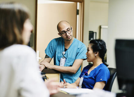 Medical staff in discussion at nurses station in hospital
