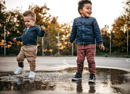 two young children standing in puddle