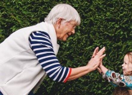older woman young child touching hands
