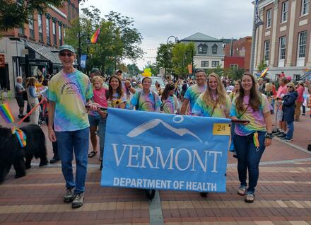 Health Dept employee with banner in Pride Parade
