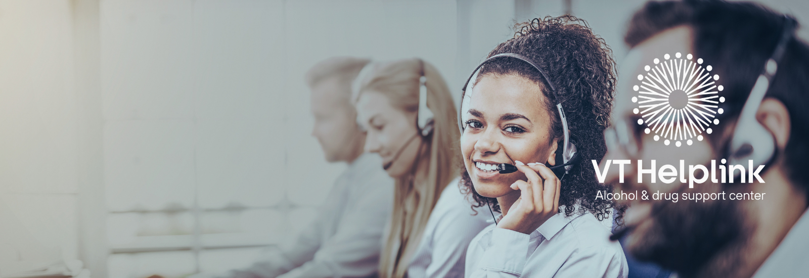 Woman in a call center smiling at the camera. VT Helplink logo. 