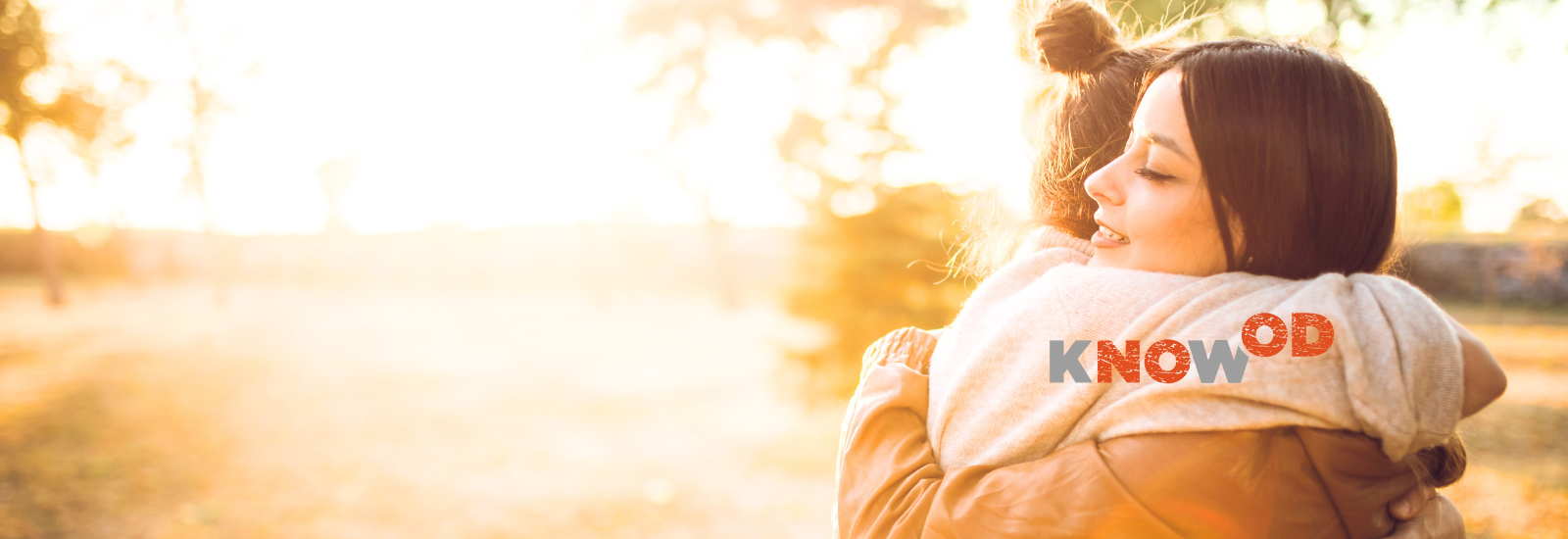 Two young women hugging on a sunny day. KnowOD logo.