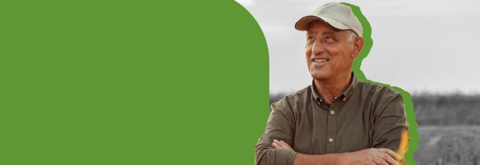 Man standing in a field, smiling with his arms comfortably crossed.