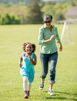 Child and adult running on a soccer field