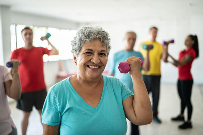 Group of adults in a room lifting small weights to show the value of upper body strengthening.