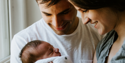 parents smiling at newborn baby