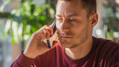 man in a red long sleeve shirt listening on a cell phone
