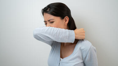 person sneezing into arm
